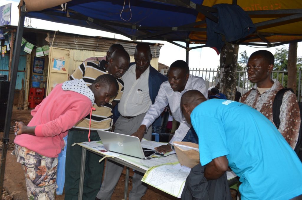 Joshua Ogure of Map Kibera demonstrate to parents how the Open Schools Kenya website works